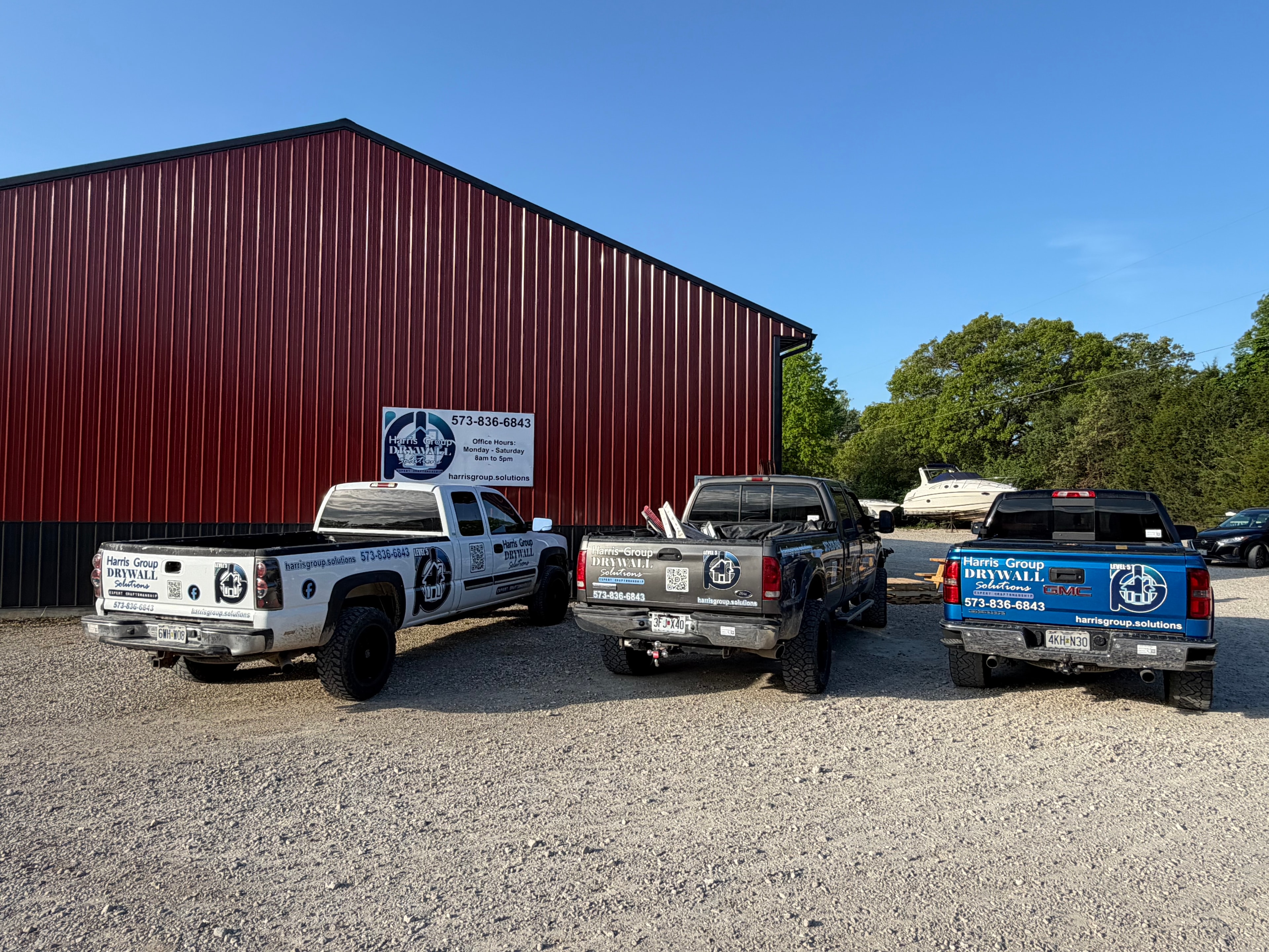Harris Group Drywall Solutions trucks lined up at a red building, 2025